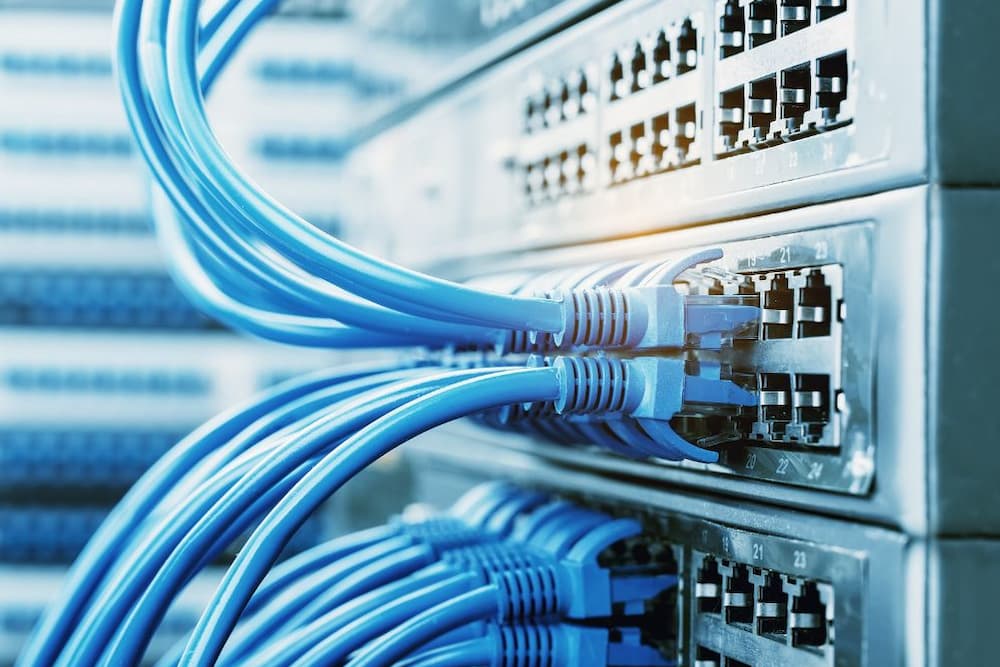 Cabos de rede conectados a switches em uma estrutura de cabeamento.