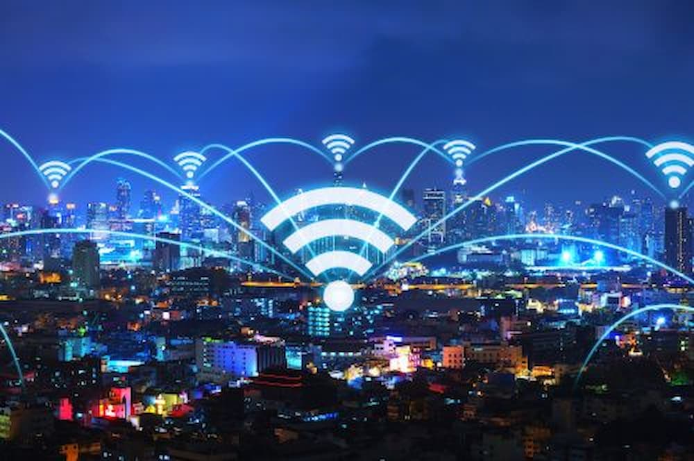 Paisagem urbana noturna com ícones de Wi-Fi interligando pontos da cidade, simbolizando conectividade.