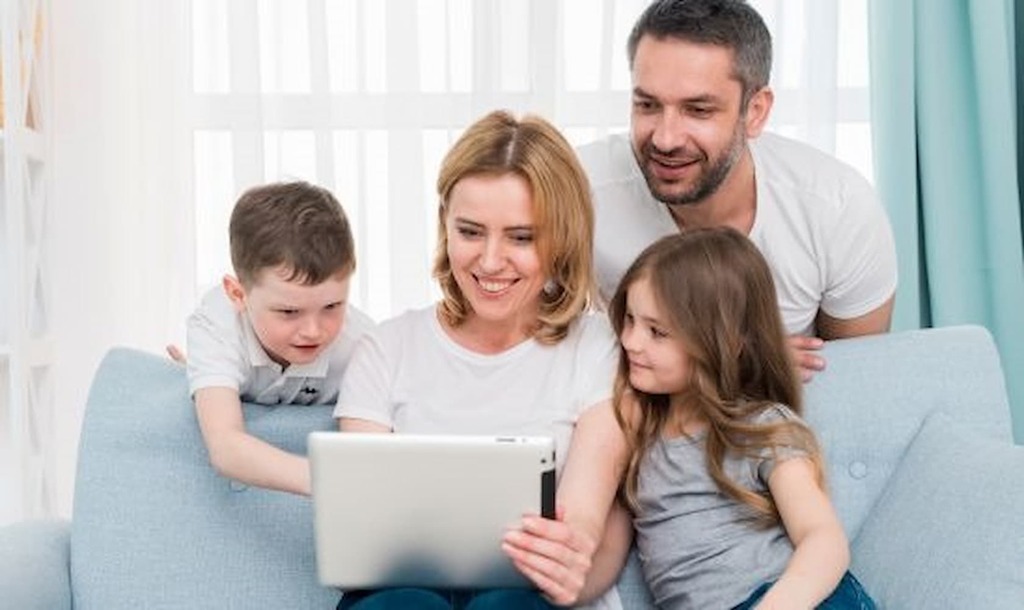 Família com dois filhos usando tablet no sofá, conectada à internet por Wi-Fi.

