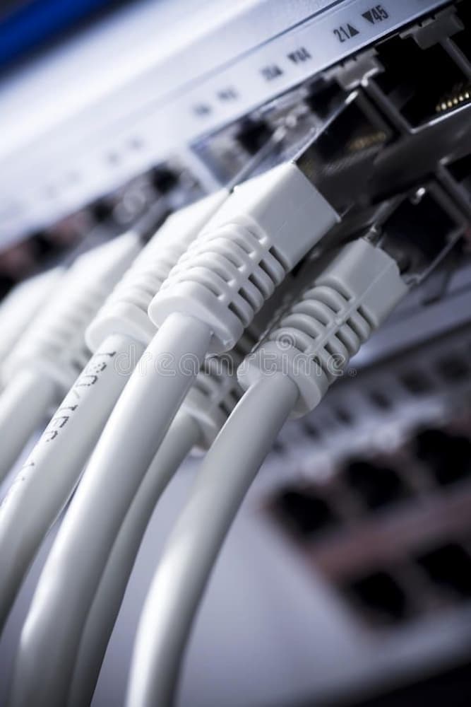 Cabos de rede RJ45 brancos conectados a switch, representando conexão estável e infraestrutura de dados para casa inteligente.