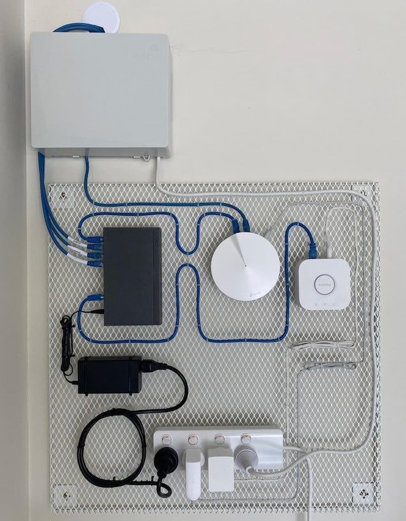 Painel com switch, roteador, hub de automação e cabos de rede organizados.